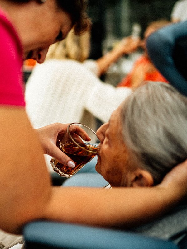Caregiver helping elderly woman drink